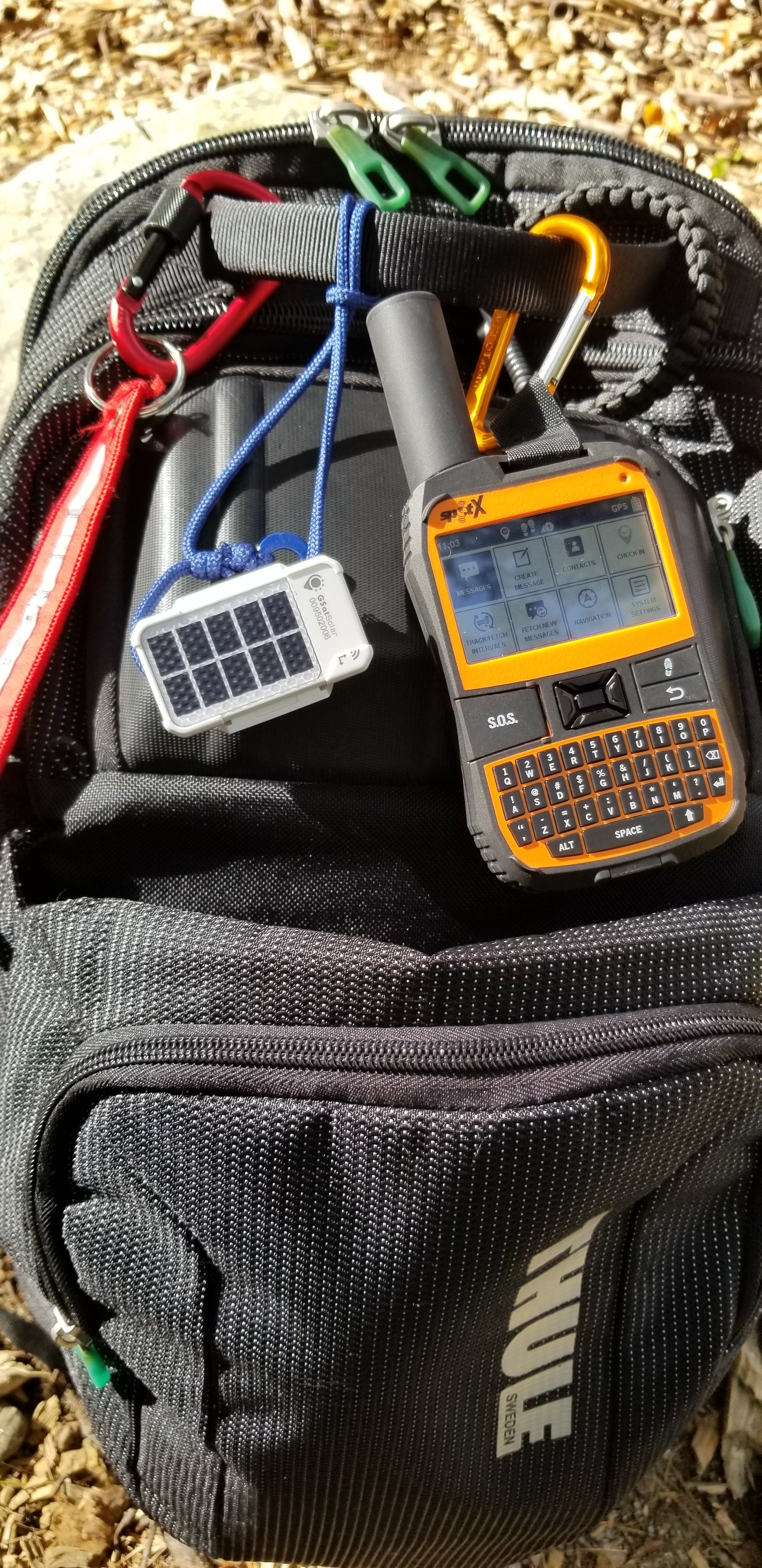 GSatSolar traceur GPS satellite solaire Globalstar accroché à un sac à dos d'expédition avec communicateur satellite SPOT X — tracking autonome pour aventuriers et randonneurs
